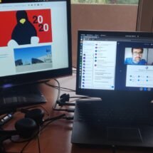 Ordenadores portátiles, uno con la página web de esLibre en la pantalla y el otro con las caras de dos hombres que van a exponer en la plataforma BigBlueButton. Se trata de la edición del congreso esLibre 2020.