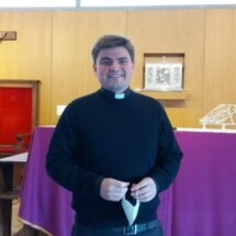 Padre Gabriel Díaz Arzola de pie, con la mascarilla de la mano y sonriendo; en la iglesia de San Vicente de Paúl de Valdemoro