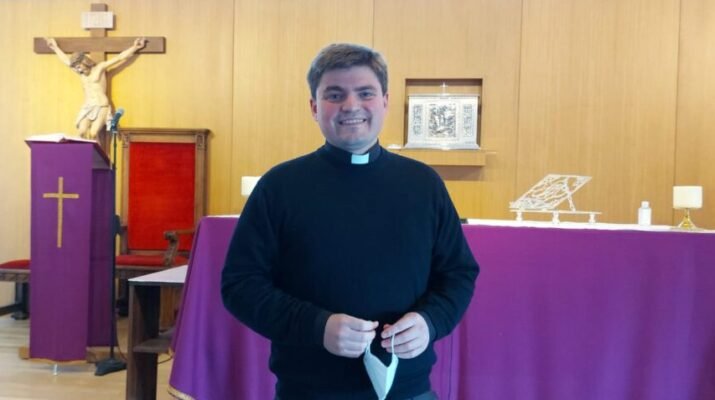 Padre Gabriel Díaz Arzola de pie, con la mascarilla de la mano y sonriendo; en la iglesia de San Vicente de Paúl de Valdemoro