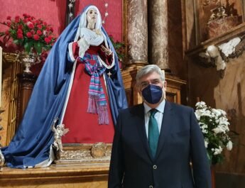 Juan Venegas, Hermano Mayor de la Hermandad de los Estudiantes de Madrid, vestido con traje y corbata. Dentro de la Basílica Pontificia de San Miguel junto a la imagen de la Virgen.