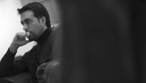 Foto en blanco y negro de Edu Bayón sentado en un sofá y mirando de lado