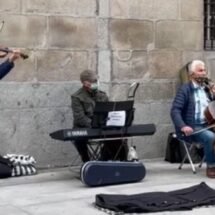 Cinco músicos callejeros tocando instrumentos como el piano y el violín a las puertas de la Academia de Bellas Artes de San Fernando
