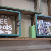 Cartel de "free book" que señala a una estantería con libros