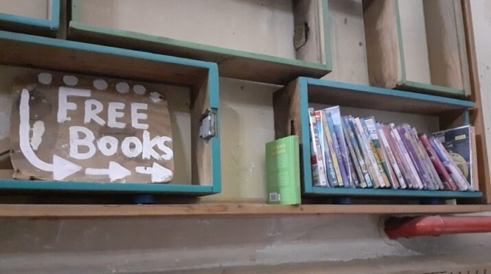 Cartel de "free book" que señala a una estantería con libros