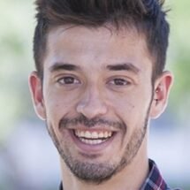 Foto de cara de Alejandro Carbonel sonriente sobre un fondo difuminado