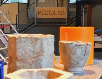 Una serie de recipientes elaborados con materiales reciclados y de fondo un cartel de Medialab