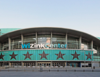 Fachada oeste del Palacio de Deportes de la Comunidad de Madrid, el Wizink Center, donde puede verse la entrada con el nombre del estadio y las estrellas características de la Comunidad de Madrid sobre un fondo azul.