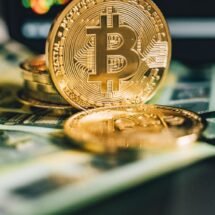 Monedas bitcoin en forma de euro, apoyadas sobre unos billetes de 100 euros.