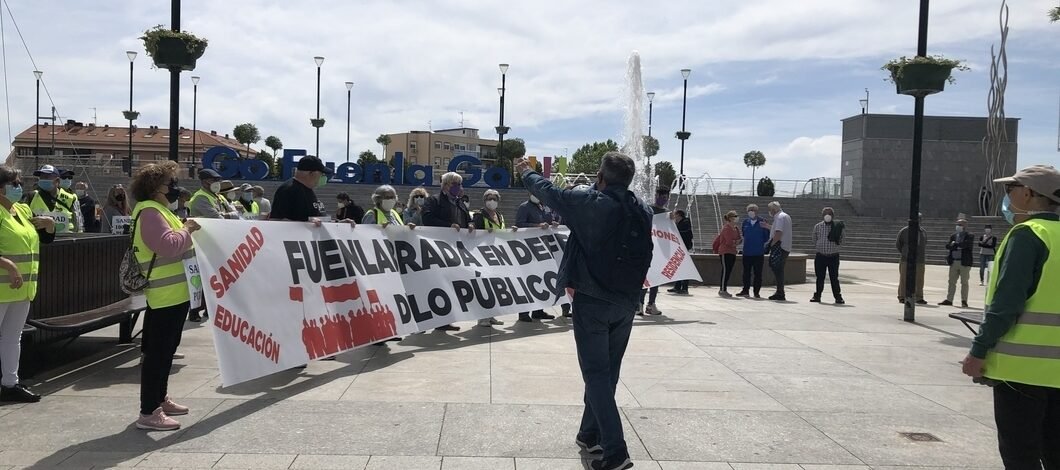 Pensionistas de Fuenlabrada, vistiendo chalecos amarillos, sujetan una pancarta en la que se lee: "Fuenlabrada en defensa de lo público". Un hombre con un megáfono corea cánticos delante de ellos.