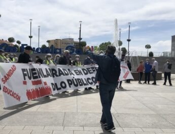 Pensionistas de Fuenlabrada, vistiendo chalecos amarillos, sujetan una pancarta en la que se lee: "Fuenlabrada en defensa de lo público". Un hombre con un megáfono corea cánticos delante de ellos.