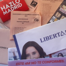 Varios sobres y papeletas de las elecciones de Madrid en 2021. Aparecen esparcidos por una mesa con luz de día.