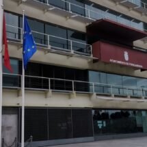 Fachada del ayuntamiento de Fuenlabrada. Se ven tres banderas. El edificio cuenta con numerosos balcones y ventanas acristaladas. En uno de ellos se ve el escudo de Fuenlabrada.