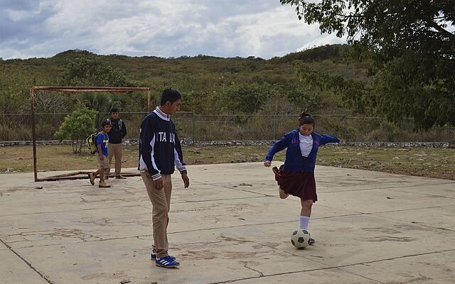 Niña jugando a fútbol con niños