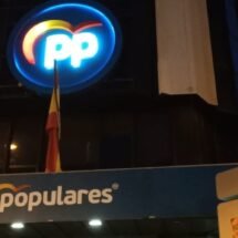 Edifico centro de Madrid. Logo corporativo PP en el centro. Balcón azúl con la palabra populares. Tarde-noche.