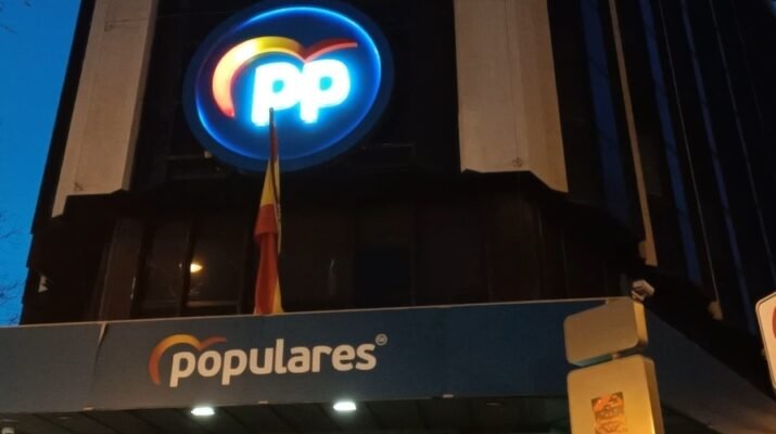 Edifico centro de Madrid. Logo corporativo PP en el centro. Balcón azúl con la palabra populares. Tarde-noche.