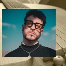 El cantante Jonathan Pons, joven moreno con barba y cabello rizado vestido de negro con una cadena al cuello y gafas mira a cámara sobre un cielo azul. Está superpuesto sobre una fotografía en sepia de una guitarra