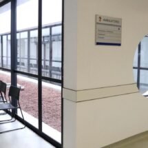 Sillas vacías en un centro médico junto a una cristalera.