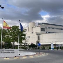 Hospital visto desde el exterior. A la izquierda una rotonda con banderas y a la derecha el edificio.