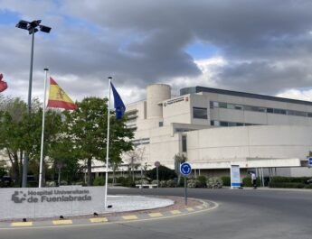 Hospital visto desde el exterior. A la izquierda una rotonda con banderas y a la derecha el edificio.