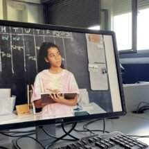 Dos pantallas de ordenador en una clase de universidad con una foto de una estudiante proyectada en la pantalla de uno de ellos