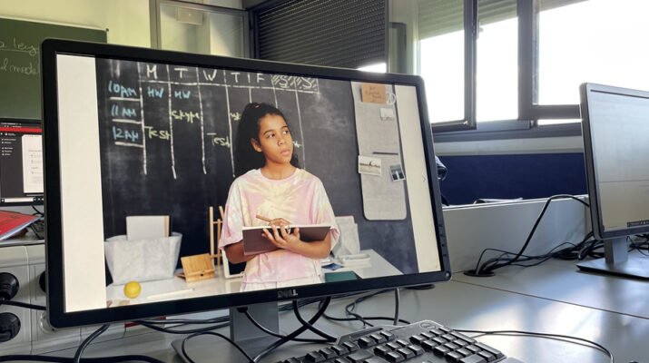 Dos pantallas de ordenador en una clase de universidad con una foto de una estudiante proyectada en la pantalla de uno de ellos