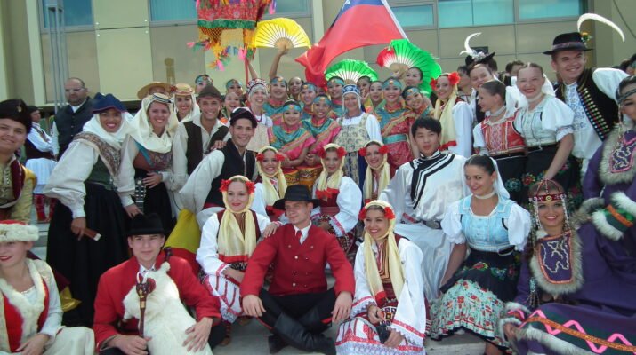 Personas de varios países posan juntas vestidas con sus trajes tradicionales en un festival de folclore.