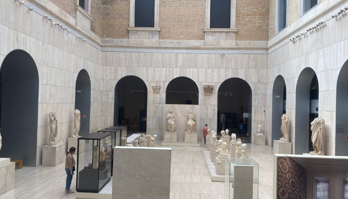 Esculturas de Livia y Tiberio, en mármol, un hombre y una mujer sentados al final de un pasillo de estatuas.
