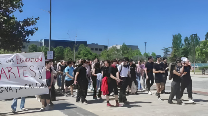 Grupo de estudiantes de Danza de la Universidad Rey Juan Carlos manifestándose en el campus de Fuenlabrada. En la parte izquierda hay una pancarta en la que pone "Por una educación en Artes digna y de calidad"