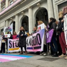 Concentración de personas trans con banderas en tonos rosas y celestes pastel y Mar Cambrollé, la representante de la Asociación de Transexuales de Andalucía- Sylvia Rivera, en el centro pronunciando un discurso en la Madrid, a 9 de enero de 2024.