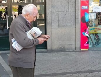 Pensionista en la calle mirando el teléfono
