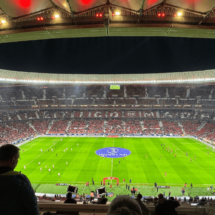 Imagen del terreno de juego y panorámica de la grada del Estadio Metropolitano, donde se puede ver a personas asistentes a un partido y una tela en el centro del campo.