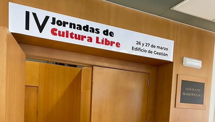 En la imagen se observa la puerta de entrada a las IV Jornadas de Cultura Libre con un cartel en la parte superior de la puerta indicando el evento.