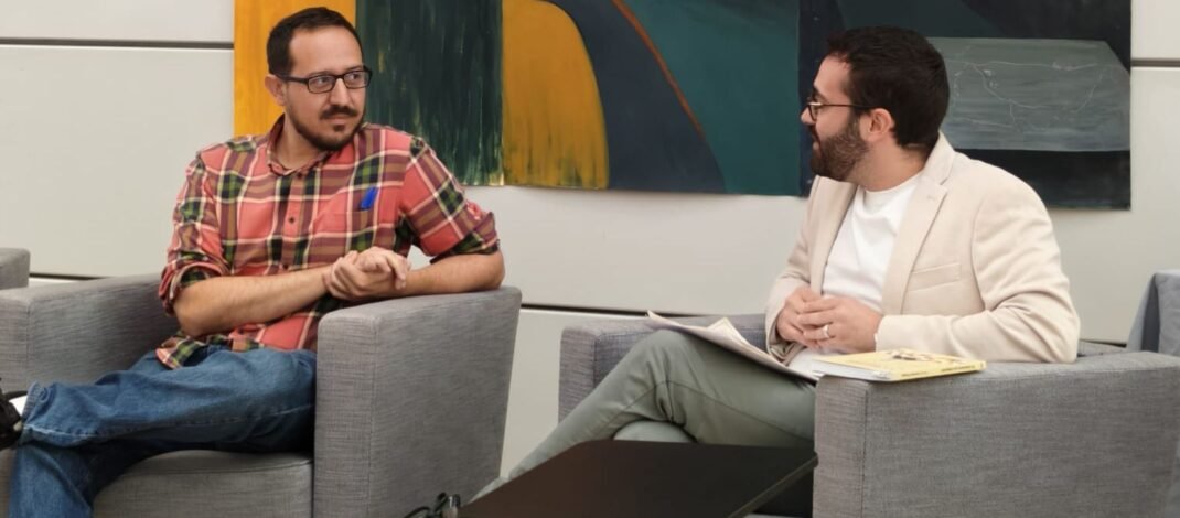 Escudero Paniagua y Silvestre Llamas están charlando, sentados en dos sillones grises, en la presentación del libro
