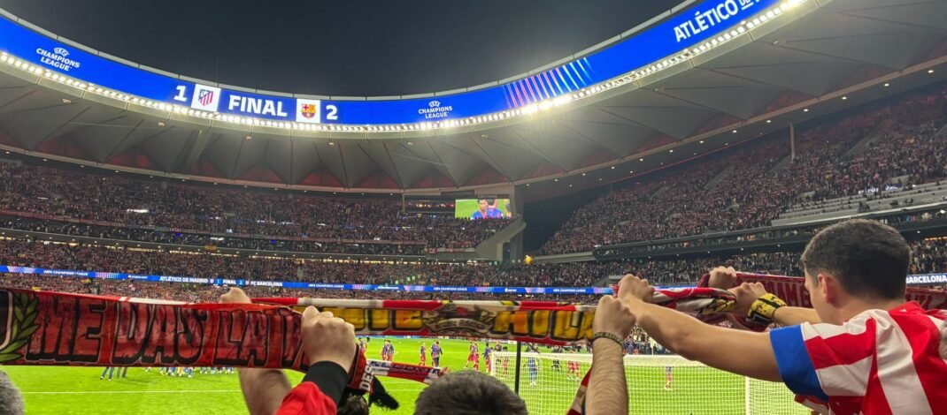 La hinchada atlética alza sus banderas y bufandas. Al fondo, se ve el resultado en el videomarcador.