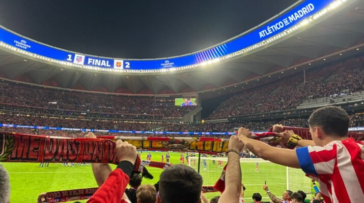 La hinchada atlética alza sus banderas y bufandas. Al fondo, se ve el resultado en el videomarcador.