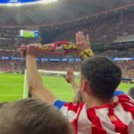 Un aficionado levanta su bufanda a pie de campo