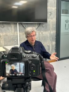 Javier de la Cueva detras de una cámara mientras da su entrevista, sentando en una silla en una habitacion cerrada.