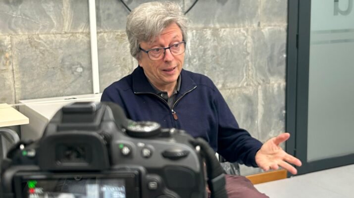 Javier de la Cueva detras de una cámara mientras da su entrevista, sentando en una silla en una habitacion cerrada.
