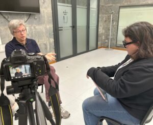 Javier de la Cueva sentado siendo entrevistado por Karen Cano en una habitación cerrada. El entrevistado está de frente y el entrevistador de perfil