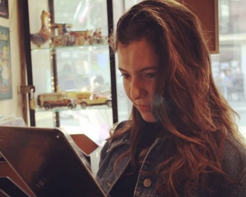 Mujer joven, con mirada baja, leyendo un papel