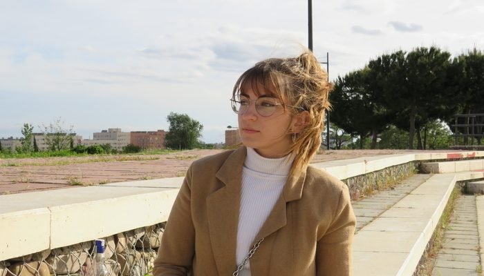 Chica joven con una chaqueta marrón y camiseta blanca